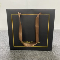Sac en papier recyclé noir mat durable avec impression sérigraphiée en relief et poignées en ruban pour l'emballage de vêtements haut de gamme