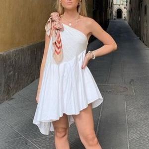 ชุดเดรสสั้นสีขาวแบบไหล่เดียวสำหรับผู้หญิง รุ่นใหม่ปี 2026 แบบ OEM สั่งทำพิเศษ พร้อมผ้าพันคอตกแต่ง กระโปรงทรงพลิ้วแบบอสมมาตร เหมาะสำหรับใส่ไปเที่ยวพักผ่อน - Product Image 2
