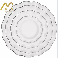 Assiettes de présentation en céramique blanches modernes à bord ondulé avec rebord noir/doré, vaisselle festonnée pour la location d'événements, mariages et fêtes, décoration de table