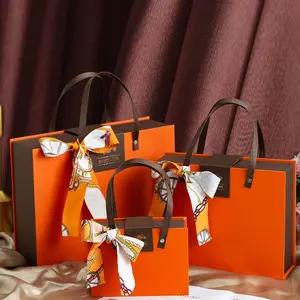 Confezione regalo di lusso con chiusura a calamita in cartone arancione con fiocco in nastro decorato con confezione regalo di nozze con manico