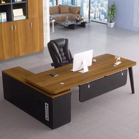 Bureau de direction moderne noir et blanc contrasté avec pieds métalliques inclinés, passe-câbles rond, armoire latérale, table de PDG/directeur