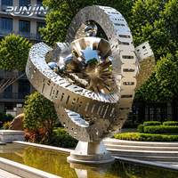 Grande sculpture sphérique creuse en acier inoxydable poli miroir, avec ruban métallique entrelacé, Art métallique Orb, Fabrication sur mesure pour place publique