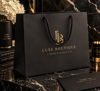 Sac de shopping en papier kraft recyclé noir mat de luxe personnalisé avec logo en feuille d'or et poignée en corde de coton pour l'emballage de vêtements