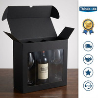 Boîte cadeau pour vin en carton ondulé noir mat avec grande fenêtre transparente en PVC et insert en mousse EVA à trois compartiments pour l'emballage d'un ensemble de bouteilles et de verres à vin