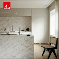Cuisine Alland moderne et minimaliste, avec panneaux plats mats couleur crème personnalisés, îlot et plan de travail en marbre blanc.