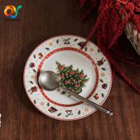 Assiette de Noël en céramique style rétro, motif de conte de fées avec Père Noël, cheval à bascule, sapin, agneau de Noël, et bordure géométrique rouge, idéale pour les fêtes