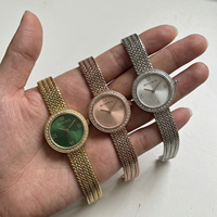 Montre-bracelet élégante pour femme en acier inoxydable avec logo personnalisé OEM, cadran doré, mouvement à quartz, lunette sertie de diamants et bracelet milanais en maille.