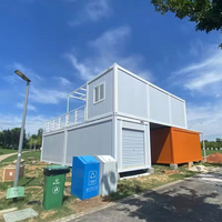 Maison conteneur démontable, panneau gris clair, porte bleue, cabine à deux niveaux avec fenêtre pour l'hébergement de campements de travailleurs