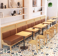 Banquette en bois de style Japandi avec dossier en rotin et chaises à coussin en cuir avec tables à piétement noir pour café
