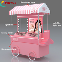 Chariot de présentation mobile haut de gamme rose personnalisé pour cosmétiques et parfums, avec auvent et roues, idéal pour les événements en centre commercial