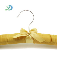 Cintre rembourré en satin jaune doré avec nœud décoratif et crochet argenté pour le rangement des robes en soie dans les chambres d'hôtel