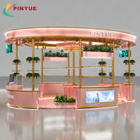Kiosque de présentation de cosmétiques de luxe en or rose pour centre commercial, avec auvent LED ovale, comptoirs d'exposition incurvés, étagères en verre