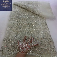 Tissu en dentelle brodée de perles et de sequins en cristal argenté sur maille avec bord festonné pour robe de mariée ou de soirée