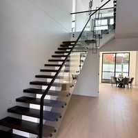 Escalier flottant moderne avec marches en chêne massif, garde-corps en verre, main courante noire, design personnalisé pour villa de luxe, penthouse, hall d'hôtel