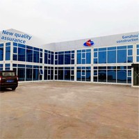 Grande structure de bureau modulaire préfabriquée en conteneurs en forme de L sur deux étages, avec façade en verre bleu, fenêtres à auvent, maison mobile et portable