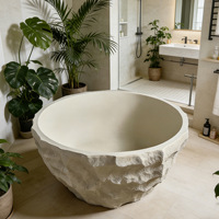 Baignoire autoportante artistique de style Wabi-sabi moderne et minimaliste, en pierre naturelle, avec détails en galets, capacité pour deux personnes
