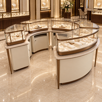 Ensemble de vitrines à bijoux sur mesure, vitrine incurvée en verre, disposition circulaire, base de rangement blanc crème, métal doré pour les bijouteries haut de gamme