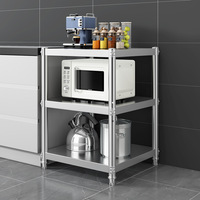 Estante de almacenamiento de cocina de acero inoxidable con tres niveles de estanterías para artículos diversos y platos.