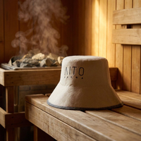 Un gorro de sauna de lana pura color crema que convierte la lambda griega en un distintivo de marca y convierte cada sala de vapor en una declaración de diseño.