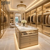 Dressing sur mesure avec finitions or champagne, îlot à bijoux en marbre et système de rangement en verre éclairé