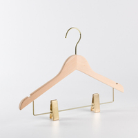Cintres en bois massif naturel avec logo personnalisé, rainures en U et pinces métalliques rembourrées pour pantalons, jupes et présentation en boutique