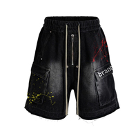 Shorts cargo vintage délavés à dégradé noir, avec détails éclaboussés de peinture, fermeture éclair, poches utilitaires et ourlet effiloché.