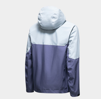 Veste à capuche bicolore bleu glace et violet, poche zippée sur le bras, poches latérales zippées, coupe-vent technique color block