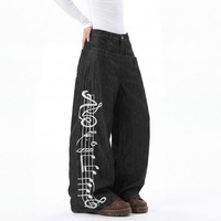 Jean déstructuré à taille asymétrique et boutonnage, avec broderie lourde de notes de musique sur portes-staves, coupe ample et fluide, pantalon long droit