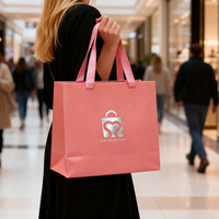 Sac spécial en lin rose à texture grainée, aspect de qualité cadeau, avec poignée en ruban estampé argenté, prêt pour les comptoirs de boutiques.