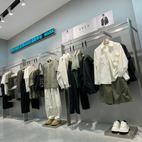 Boutiquede vêtements d'affairesélégants avecaffichage en métalnoir, cintres linéaires et unités de rangement à plusieurs niveaux