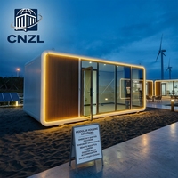 Cabane préfabriquée moderne CNZL blanche et noire avec façade entièrement vitrée, unité modulaire portable pour maison d'hôtes de station balnéaire