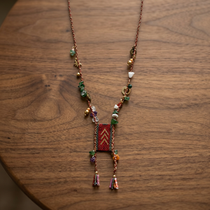 Collier artisanal Sstringz en perles Miyuki Delica rouge bordeaux avec éclats de pierre verte, breloques dorées et pompons multicolores style bohème - Product Image 1