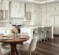 Armoire de cuisine sur mesure de luxe blanche à panneaux surélevés avec porte en verre décorative, quincaillerie dorée, grand îlot de cuisine pour la rénovation de la maison