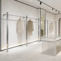 Présentoir mural de luxe léger en acier inoxydable brossé pour vêtements et robes de mariée, idéal pour les magasins de prêt-à-porter féminin
