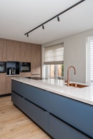 Ensemble d'armoires de cuisine sur mesure en finition bleu foncé avec évier en cuivre, plaque de cuisson à induction et four encastré