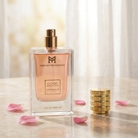 Parfum féminin, flacon rectangulaire en verre transparent, liquide rose, capuchon doré à nervures, boîte à ruban, parfum floral aux pétales