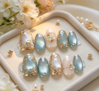 Ongles courts ovales minimalistes style Instagram, motif œil de chat vert raisin, fleur dorée 3D, paillettes, strass et fragments de perles