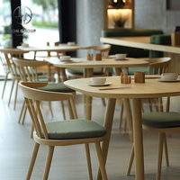 Ensemble de meubles pour café, restaurant, salon de thé : fauteuils en cuir vert avec pieds en bois, tables rectangulaires en bois et canapé banquette vert.