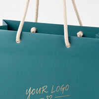 Sacs cadeaux en papier bleu sarcelle avec logo personnalisé KM, poignée en corde de coton crème, cœur en feuille d'or, pour boutique et vente au détail