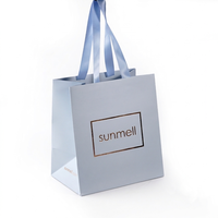 Sac shopping en papier bleu clair de luxe avec logo personnalisé en feuille d'or et poignée en ruban de satin bleu pour l'emballage de produits cosmétiques de boutique