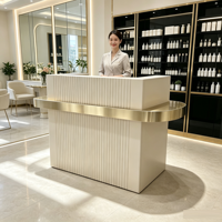 Comptoir de réception rose sur mesure haut de gamme avec panneau à rayures minimalistes et décoration dorée pour salon, spa, centre de beauté et bien-être
