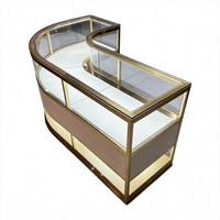 Ensemble de présentoirs de bijouterie moderne avec cadre doré, écoresponsable, éclairage LED, îlot central incurvé et vitrines périmétriques pour la vente au détail de luxe