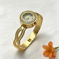 Montre bracelet pour femme à cadran rond incrusté de diamants, motifs ajourés multiples, bracelet en acier titane doré brillant