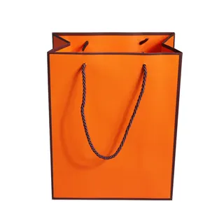 Bolsa de compras de papel de regalo de embalaje naranja de boutique de zapatos con logotipo personalizado de marca de lujo para ropa