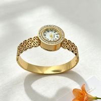 Montre bracelet pour femme à cadran rond incrusté de diamants, motifs ajourés multiples, bracelet en acier titane doré brillant