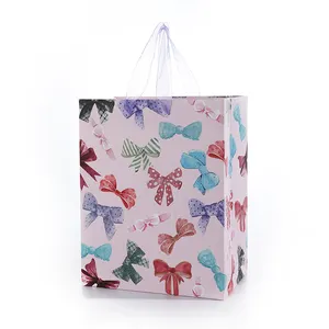 फैशनेबल धनुष पैटर्न हैंडबैग वेलेंटाइन डे उपहार बैग गॉज हैंडल के साथ सुंदर 210gsm सफेद कार्ड पेपर बैग