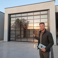 Porte de garage sectionnelle moderne à cadre fin et vue panoramique en verre, en aluminium anodisé et verre trempé, pour extérieur d'appartement
