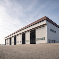 Grand hangar multi-baies pour avions avec cinq portes larges, fenêtres de pignon, aile avant et accès sur l'aérodrome