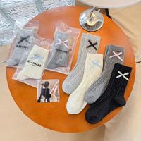 Nouvelles chaussettes torsadées printemps-été 2026 avec nœud, longueur mi-mollet, pour femme, vente en gros, style preppy blanc, couleur unie, tricotées
