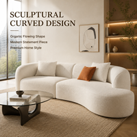 Canapé sectionnel asymétrique incurvé, texture bouclette blanche, assise profonde et confortable, design minimaliste et chaleureux.